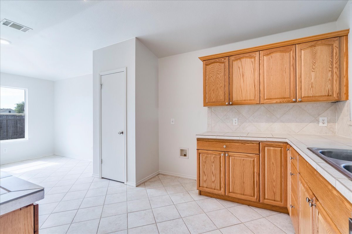 100 Easy Street Hutto, TX 78634 - Photo 9 of 36 Well-appointed kitchen featuring light wood cabinetry and crisp white tile flooring.