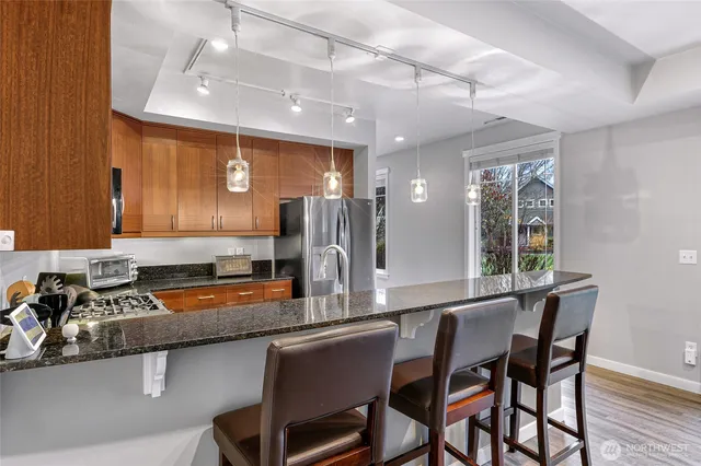 a kitchen with stainless steel appliances granite countertop a sink a stove a refrigerator cabinets and chairs
