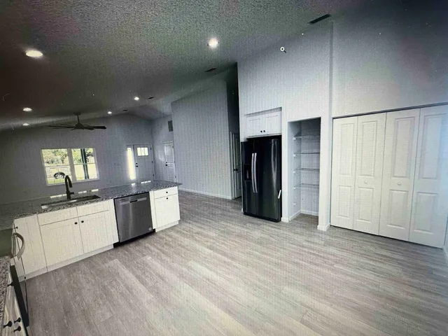 a large kitchen with a large counter top space a sink stainless steel appliances and cabinets