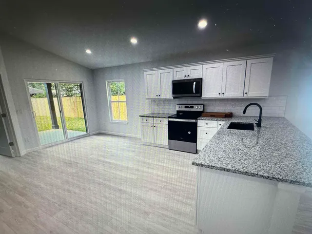 a kitchen with granite countertop a sink and a stove top oven