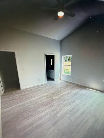 a view of an empty room with window and wooden floor