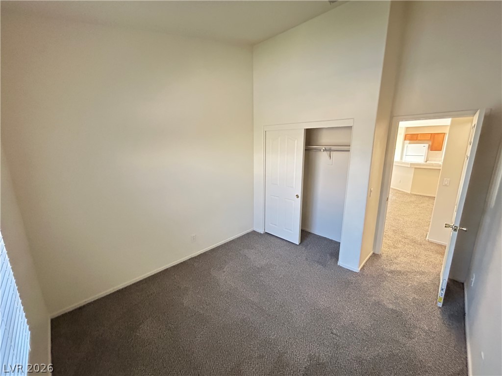 1840 Montvale Las Vegas, NV 89134 - Photo 13 of 31 A well-lit bedroom features vaulted ceilings and plush carpeting, with a view into the adjacent kitchen.