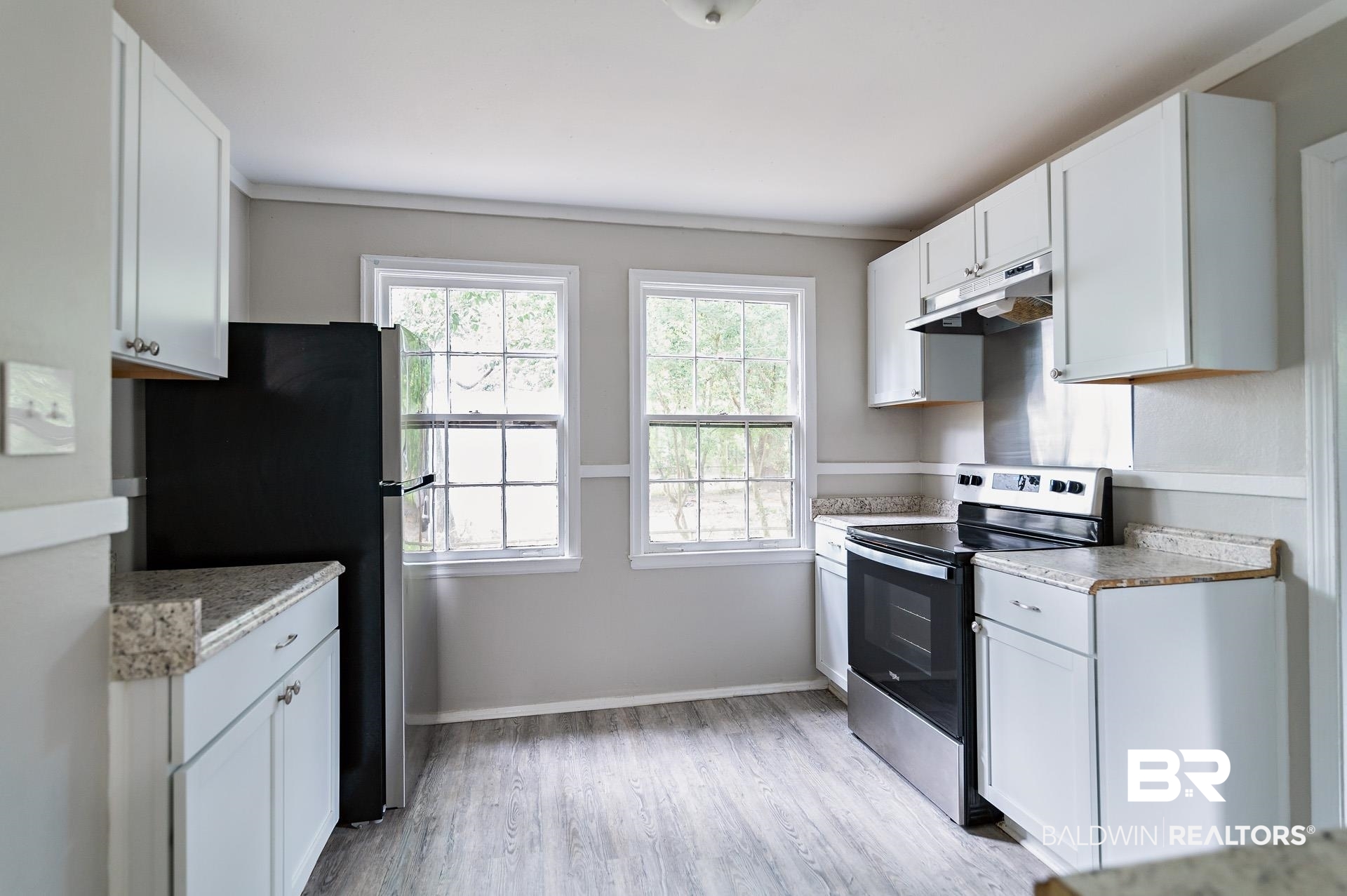 1869 Mott Drive West Mobile, AL 36617 - Photo 9 of 34 Kitchen featuring white cabinetry, appliances with stainless steel finishes, light wood-style flooring, under cabinet range hood, and baseboards
