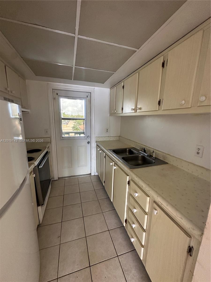 1050 East Sample Road, Unit 208 Pompano Beach, FL 33064 - Photo 3 of 9 a kitchen with a sink a stove and cabinets
