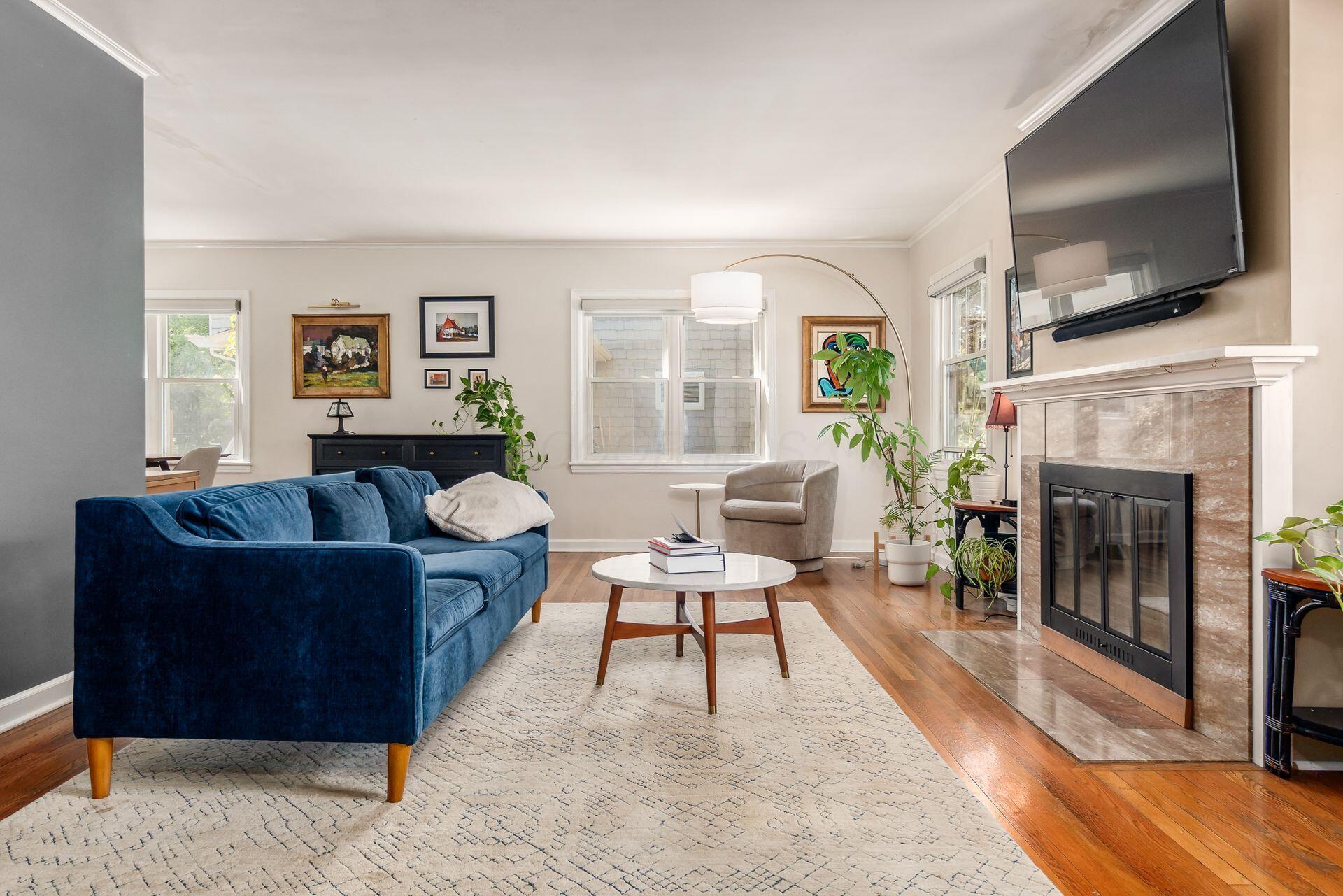 Warm family room with hardwood floors, cozy wood-burning fireplace, and seamless flow into the dining area and kitchen for effortless living