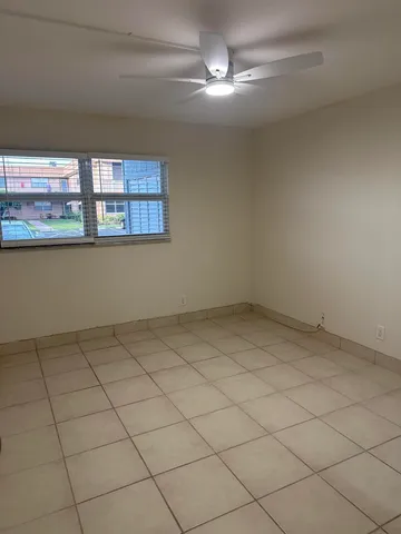 an empty room with a ceiling fan and window