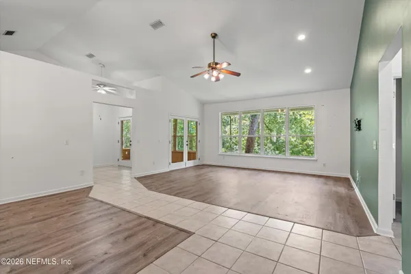 a view of an empty room with window and wooden floor