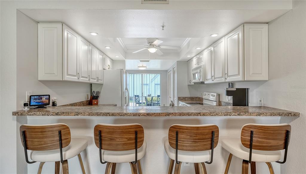 6611 Stone River Road, Unit 103 Bradenton, FL 34203 - Photo 12 of 61 a kitchen with stainless steel appliances granite countertop a table chairs sink and cabinets