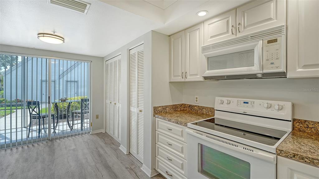 6611 Stone River Road, Unit 103 Bradenton, FL 34203 - Photo 8 of 61 a kitchen with granite countertop cabinets appliances and a wooden floor