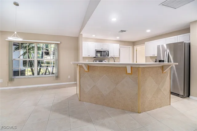 a view of a kitchen with stainless steel appliances granite countertop a refrigerator a sink a stove and white cabinets