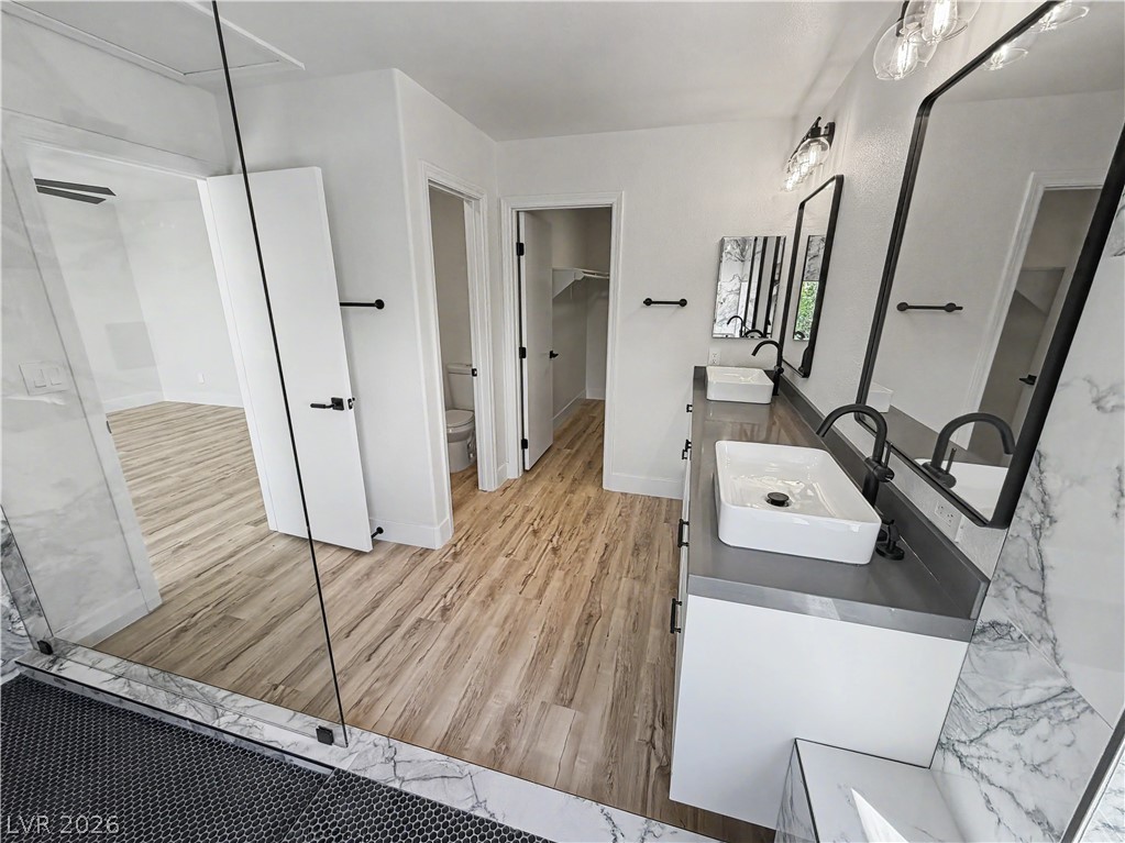 8977 Paige Rene Court Las Vegas, NV 89117 - Photo 4 of 31 Dual vessel sinks and sleek countertops enhance this contemporary primary bathroom, complete with a separate water closet.