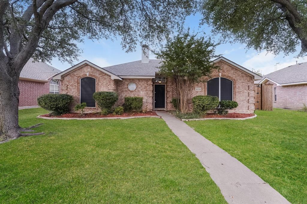 Single story home featuring a front yard, brick siding, a chimney, and a shingled roof