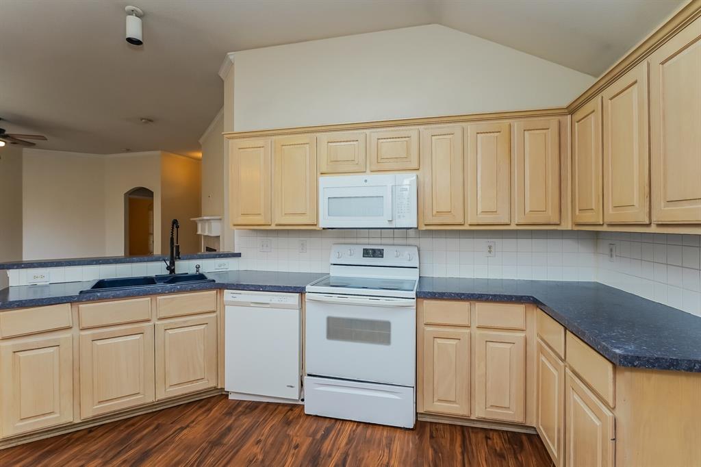10706 Robincreek Lane Frisco, TX 75035 - Photo 6 of 17 Kitchen featuring white appliances, tasteful backsplash, dark wood-type flooring, arched walkways, and a ceiling fan