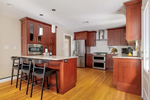 a kitchen with stainless steel appliances a stove a sink dishwasher and a refrigerator with wooden floor