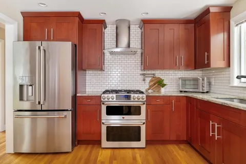 a kitchen with stainless steel appliances a refrigerator a sink and wooden cabinets
