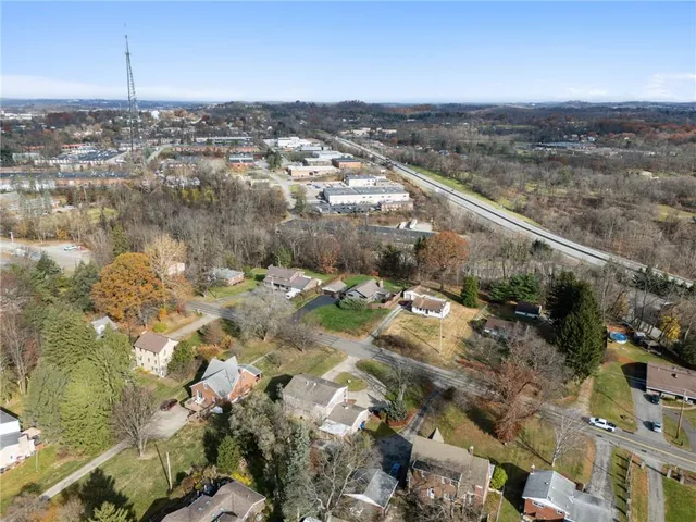 an aerial view of a house with swimming pool and large trees