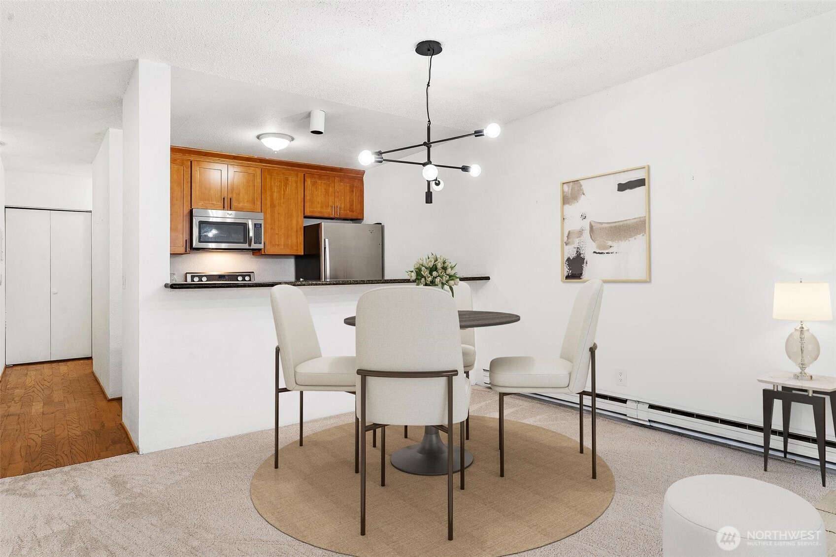 5832 Northeast 75th Street, Unit E304 Seattle, WA 98115 - Photo 10 of 36 a kitchen with stainless steel appliances granite countertop a dining table chairs and a refrigerator a mirror with wooden floors