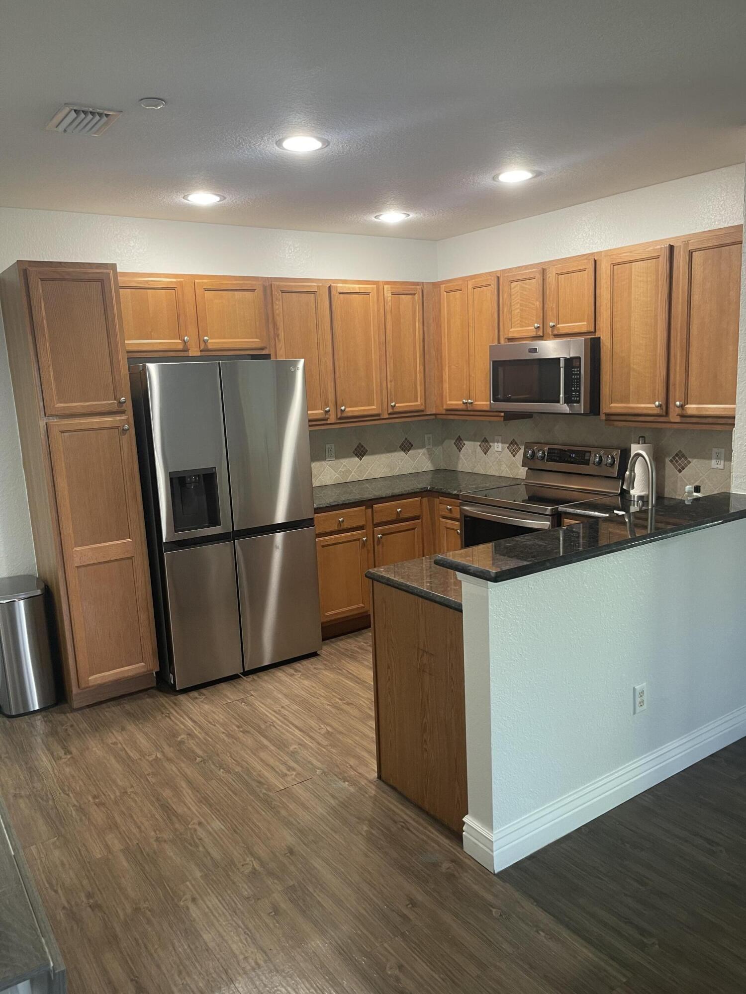 111 Stone Harbor Way, Unit F2 Delray Beach, FL 33444 - Photo 5 of 11 a kitchen with wooden cabinets and stainless steel appliances