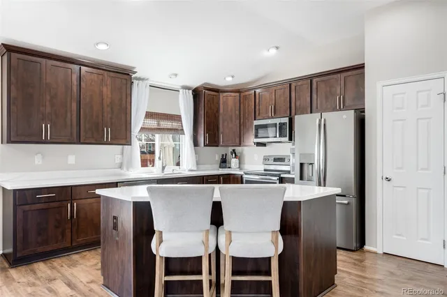 a kitchen with stainless steel appliances a refrigerator a sink a stove a dining table and chairs