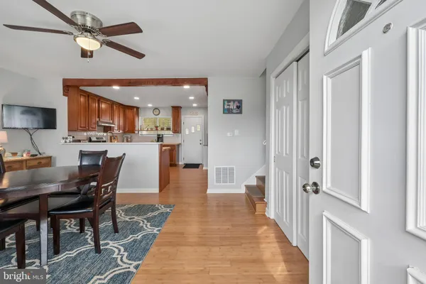 a dining room with stainless steel appliances kitchen island granite countertop a dining table chairs and a chandelier
