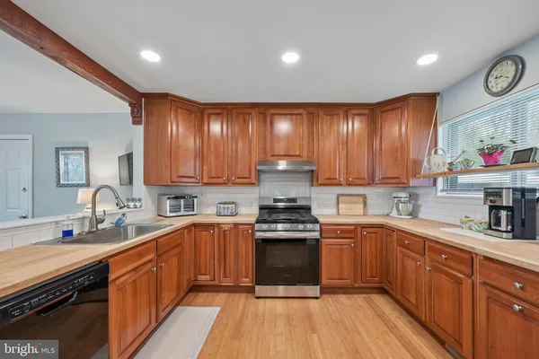 a kitchen with stainless steel appliances granite countertop wooden cabinets sink stove and microwave
