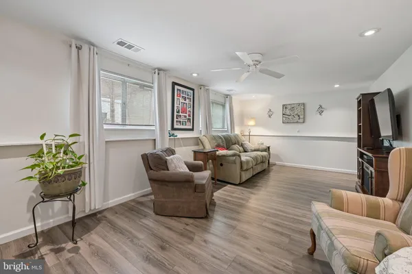 a living room with furniture a ceiling fan a flat screen tv and a window