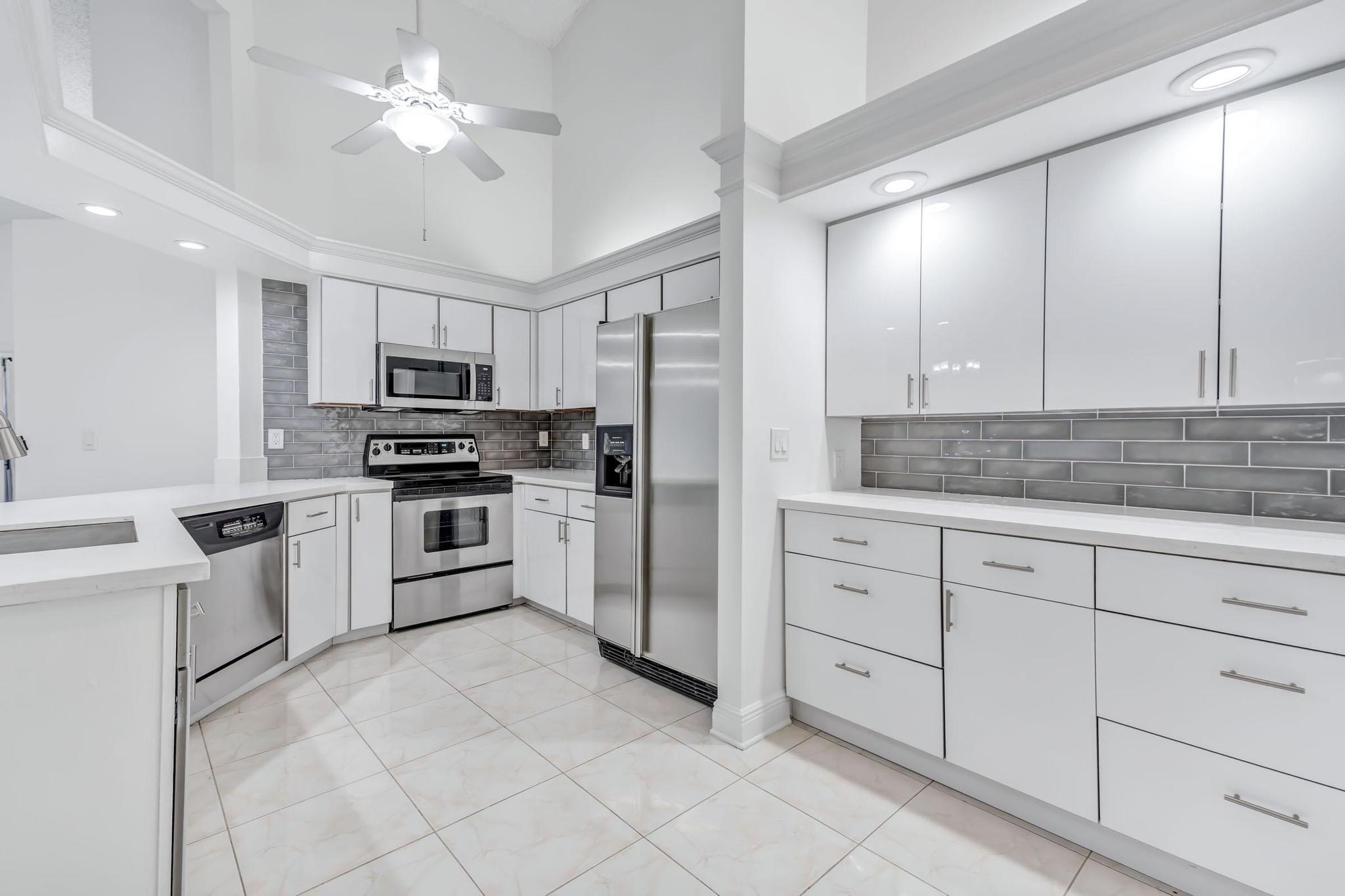 9130 Vineland Court, Unit C Boca Raton, FL 33496 - Photo 5 of 81 a kitchen with white cabinets appliances and a sink