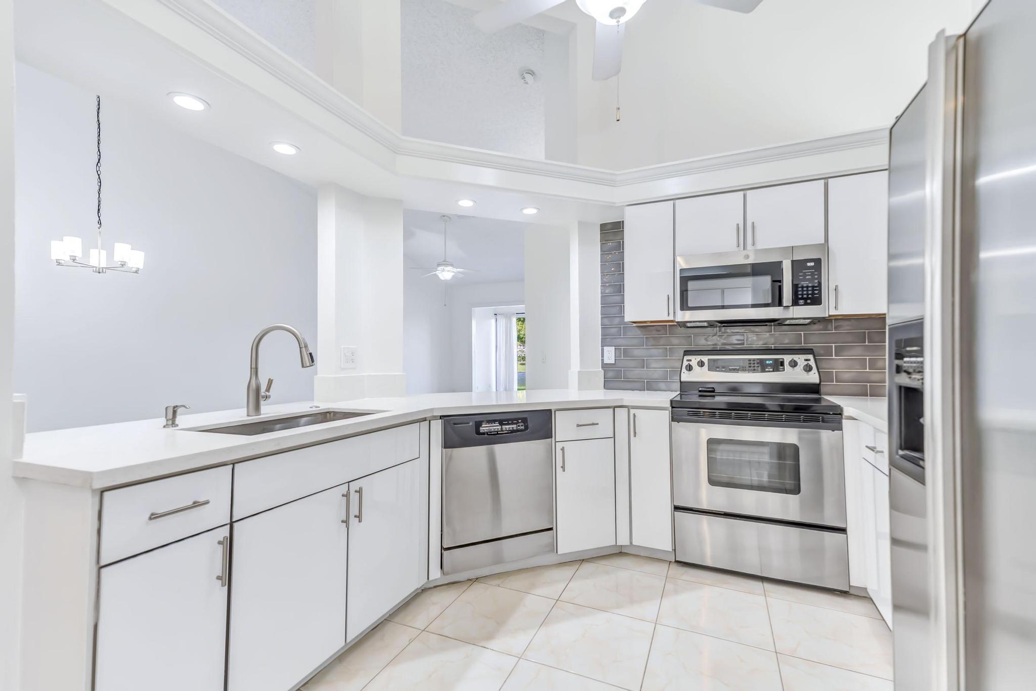 9130 Vineland Court, Unit C Boca Raton, FL 33496 - Photo 6 of 81 a kitchen with a sink and stainless steel appliances