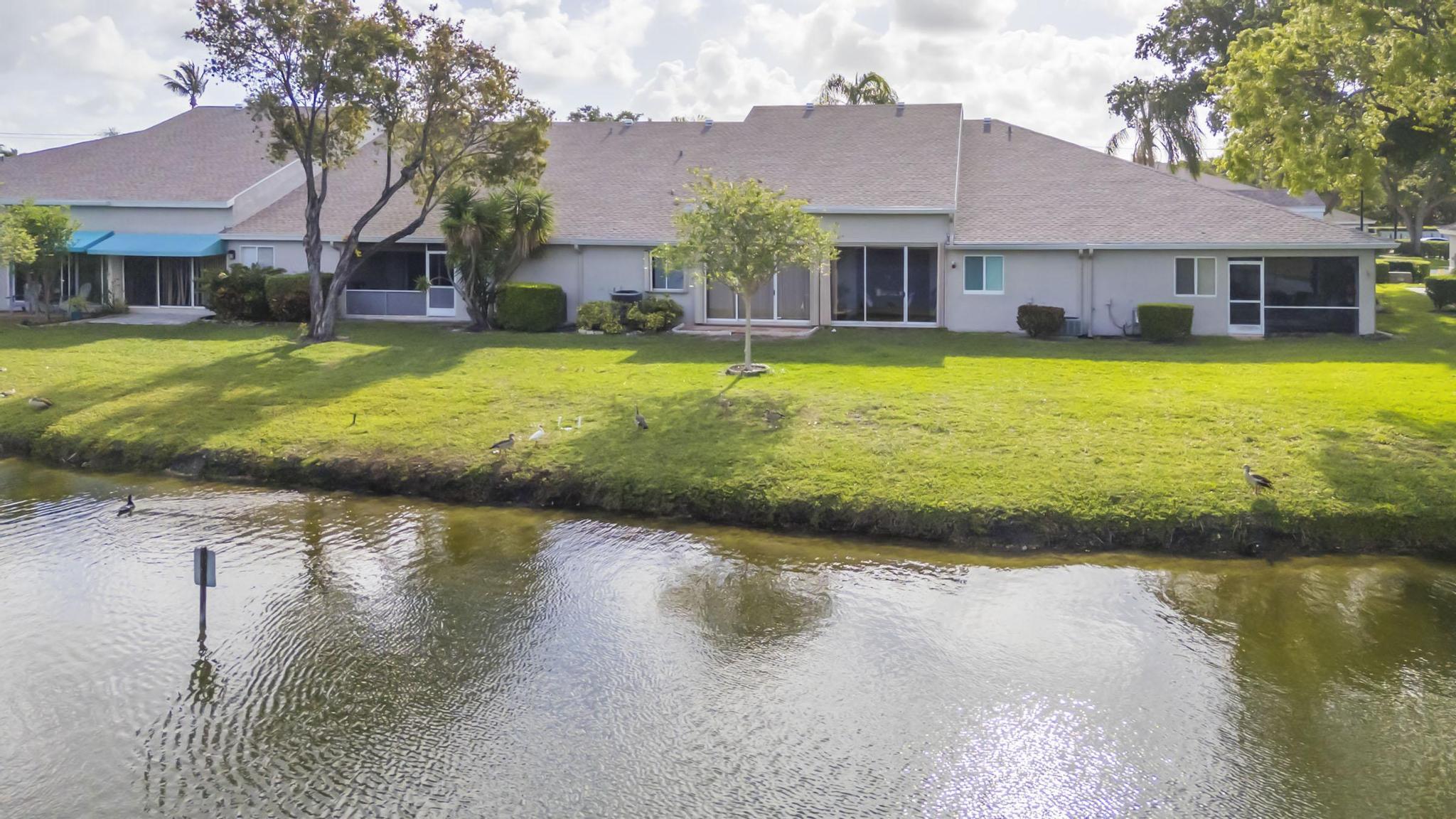 9130 Vineland Court, Unit C Boca Raton, FL 33496 - Photo 67 of 81 a view of a house with swimming pool next to a yard with plants and large trees