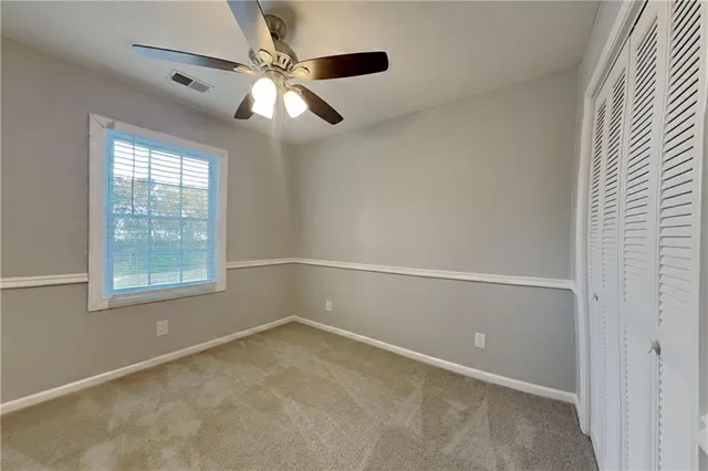 an empty room with windows and fan