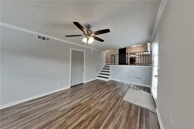 a view of a hallway with wooden floor and a ceiling fan