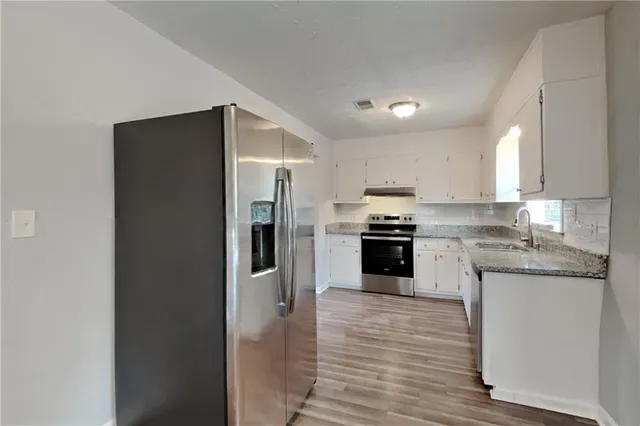 a kitchen with granite countertop a refrigerator and a stove top oven