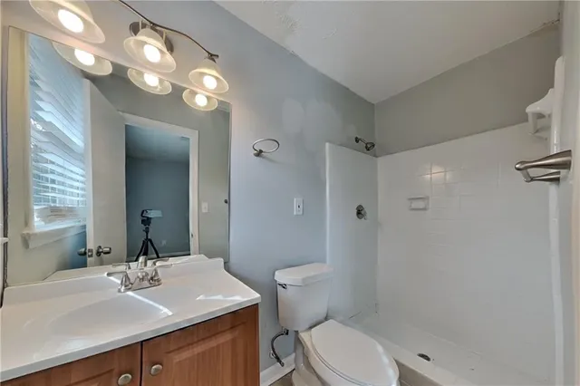 a bathroom with a sink a toilet a mirror and shower