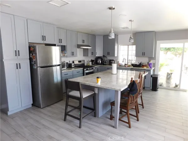 a kitchen with refrigerator a stove and white cabinets with wooden floor