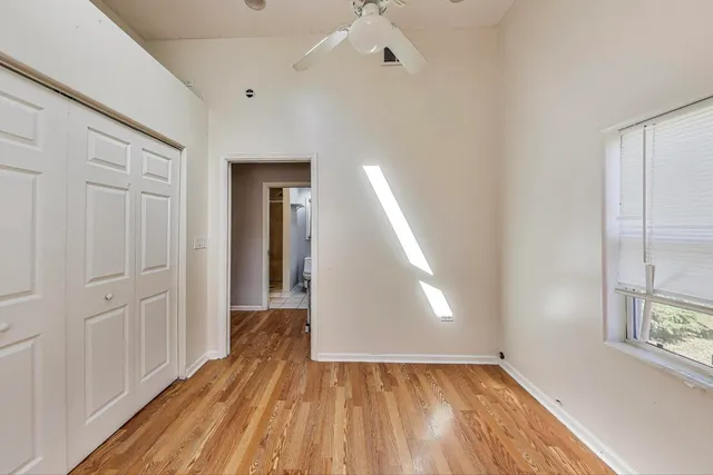 a view of empty room with wooden floor and fan