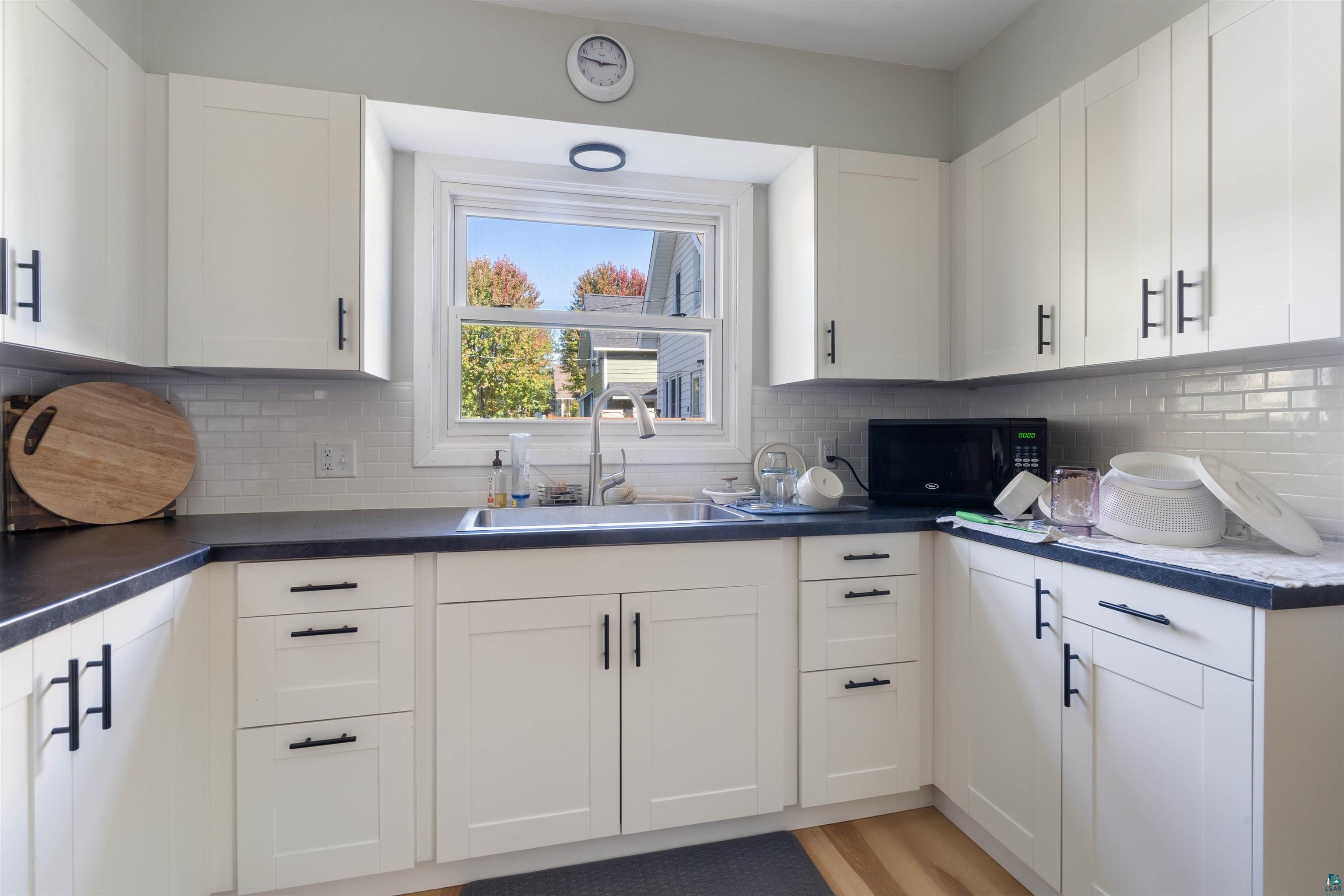3715 Rendle Avenue Duluth, MN 55803 - Photo 18 of 20 White cabinetry with matte black hardware, dark countertops, and a subway tile backsplash