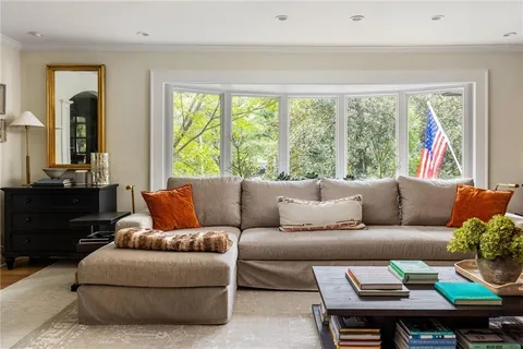 a living room with furniture a bookshelf and a large window