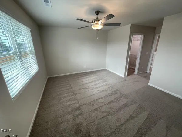 an empty room with windows and fan