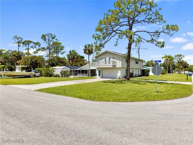 a view of a house with a big yard and palm trees