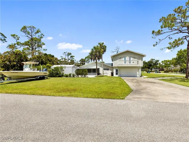 a view of a house with a big yard and palm trees