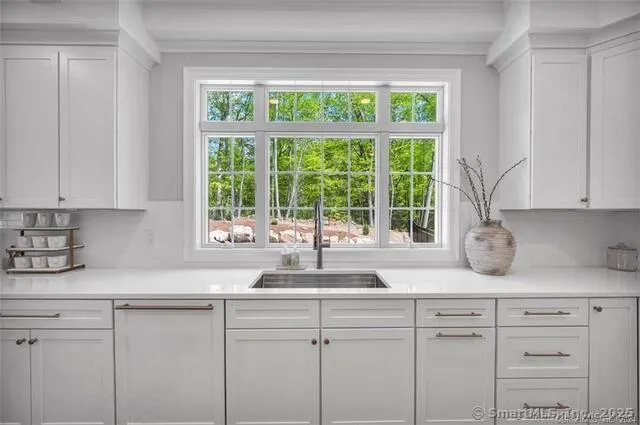 a kitchen with white cabinets and a large window