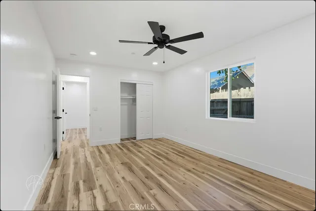 a view of empty room with wooden floor and fan