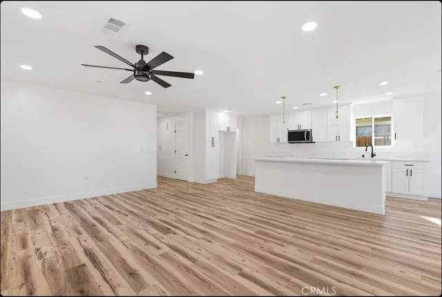 a view of a kitchen with wooden floor and stainless steel appliances
