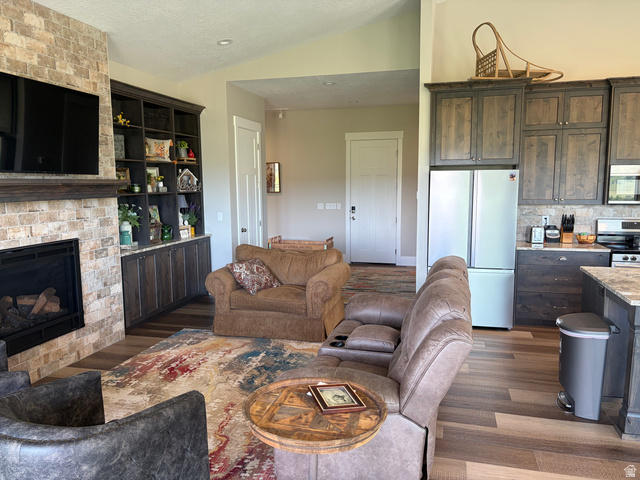 1325 South Round Road East Laketown, UT 84038 - Photo 26 of 40 Spacious open-concept interior featuring wood-finish flooring, a stone-faced fireplace with a wood mantle, custom built-in cabinetry, and a kitchen with stone-look countertops and matching backsplash