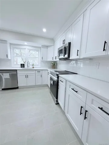 a large white kitchen with cabinets and window