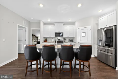 a kitchen with stainless steel appliances granite countertop a dining table chairs refrigerator microwave and cabinets