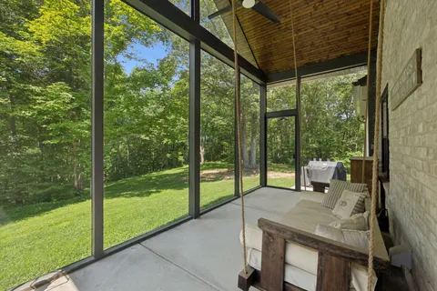 an aerial view of a house with yard and trees in the background