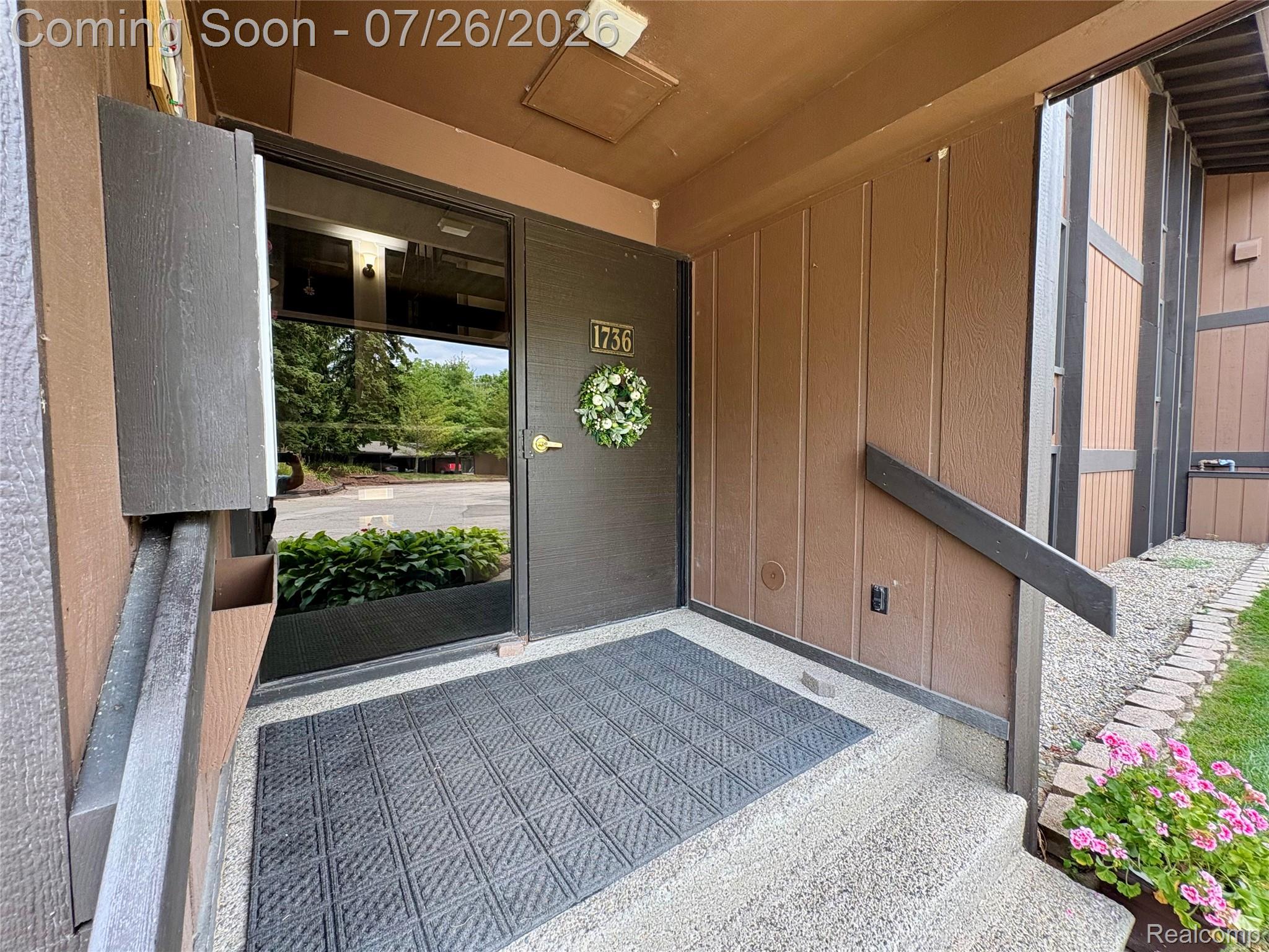 1736 Grove Road, Unit 102 Ypsilanti, MI 48198 - Photo 18 of 36 Entryway featuring textured brown siding, a full-glass entry door, and exposed aggregate concrete steps