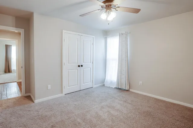 an empty room with a chandelier fan and closet area