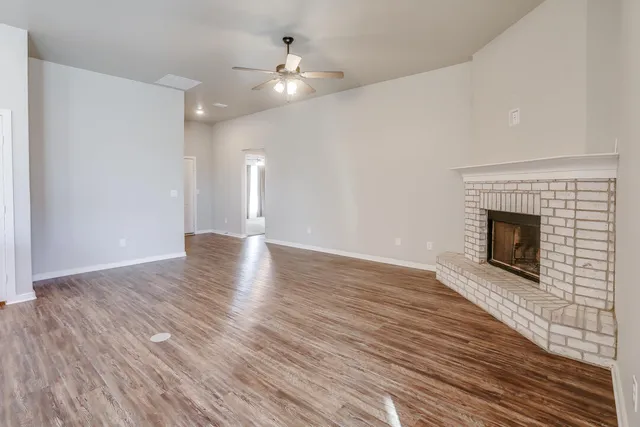a view of an empty room with wooden floor and a fireplace